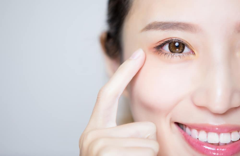 Smiling woman resting face on hands after Pasadena Blepharoplasty in Pasadena, CA
