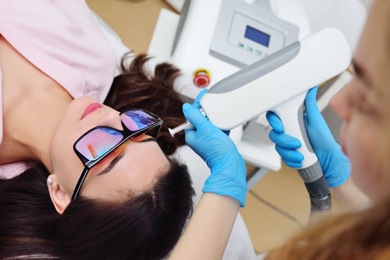 Dermatologist removing a mole on a female patient