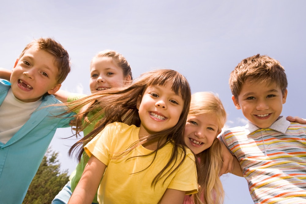 Picture of 5 kids with clear skin smiling, showing the importance of pediatric dermatology in Pasadena