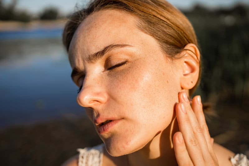 Woman showing left side of her skin with sun damage